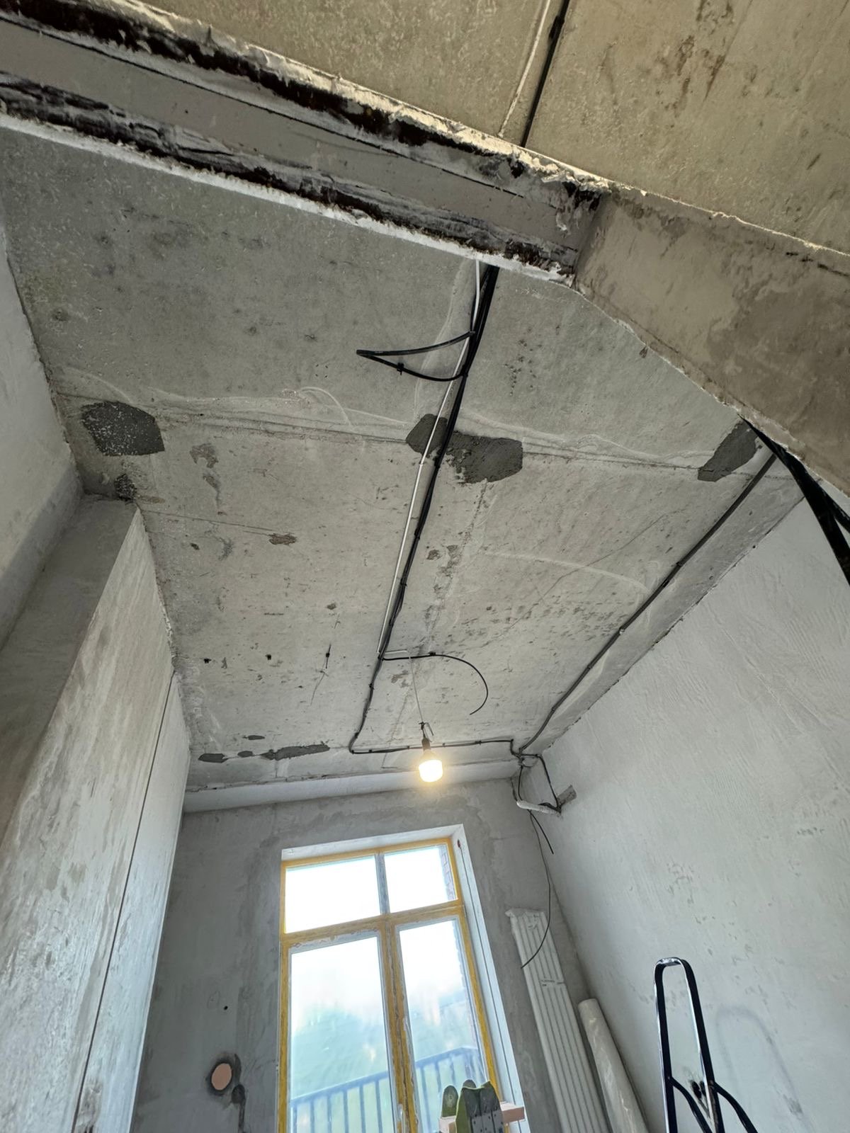 Электропроводка под потолком в строящемся помещении. Кабели в гофротрубе, бетонное перекрытие, окно.