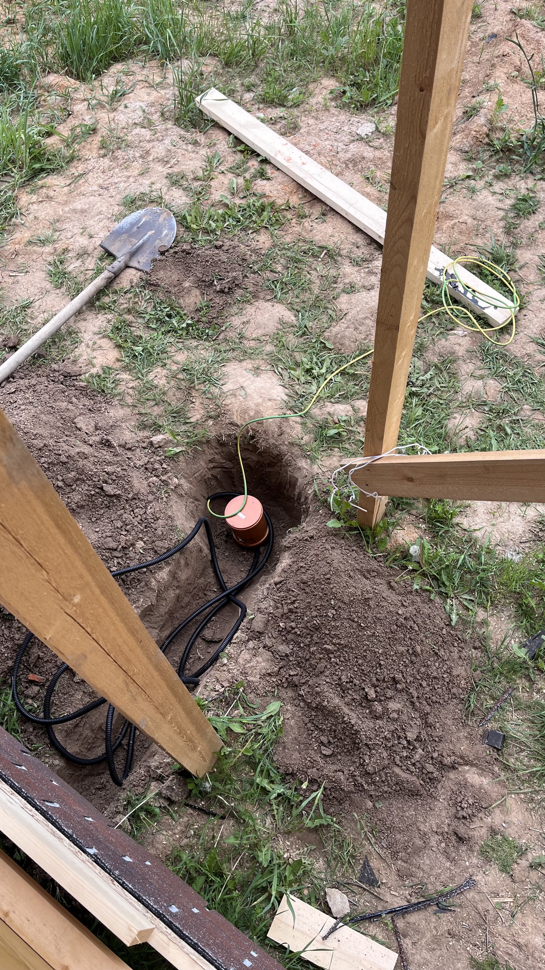 Заземление в земле: красный заземлитель, провода и инструменты.